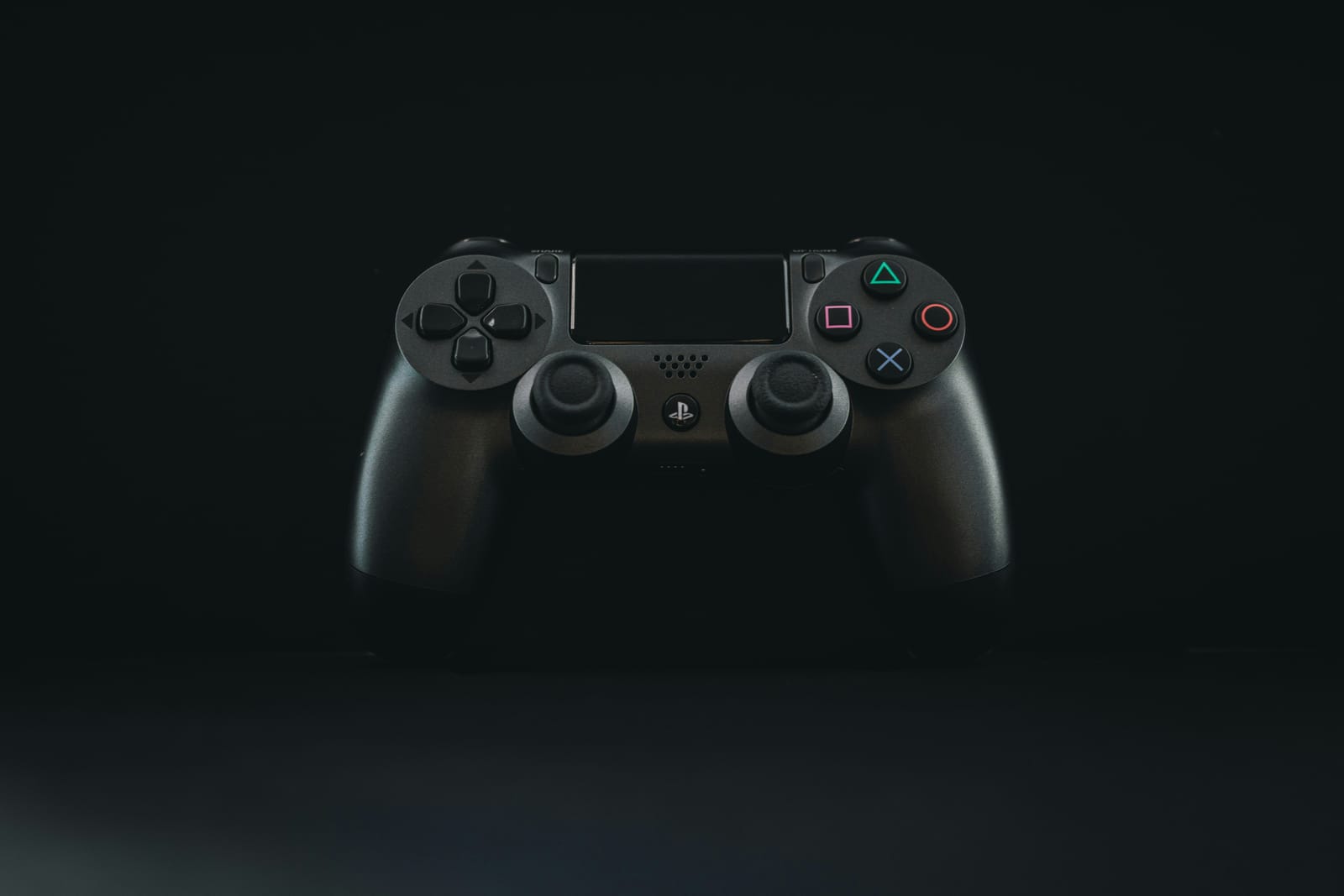 A black PlayStation controller lit against a dark background