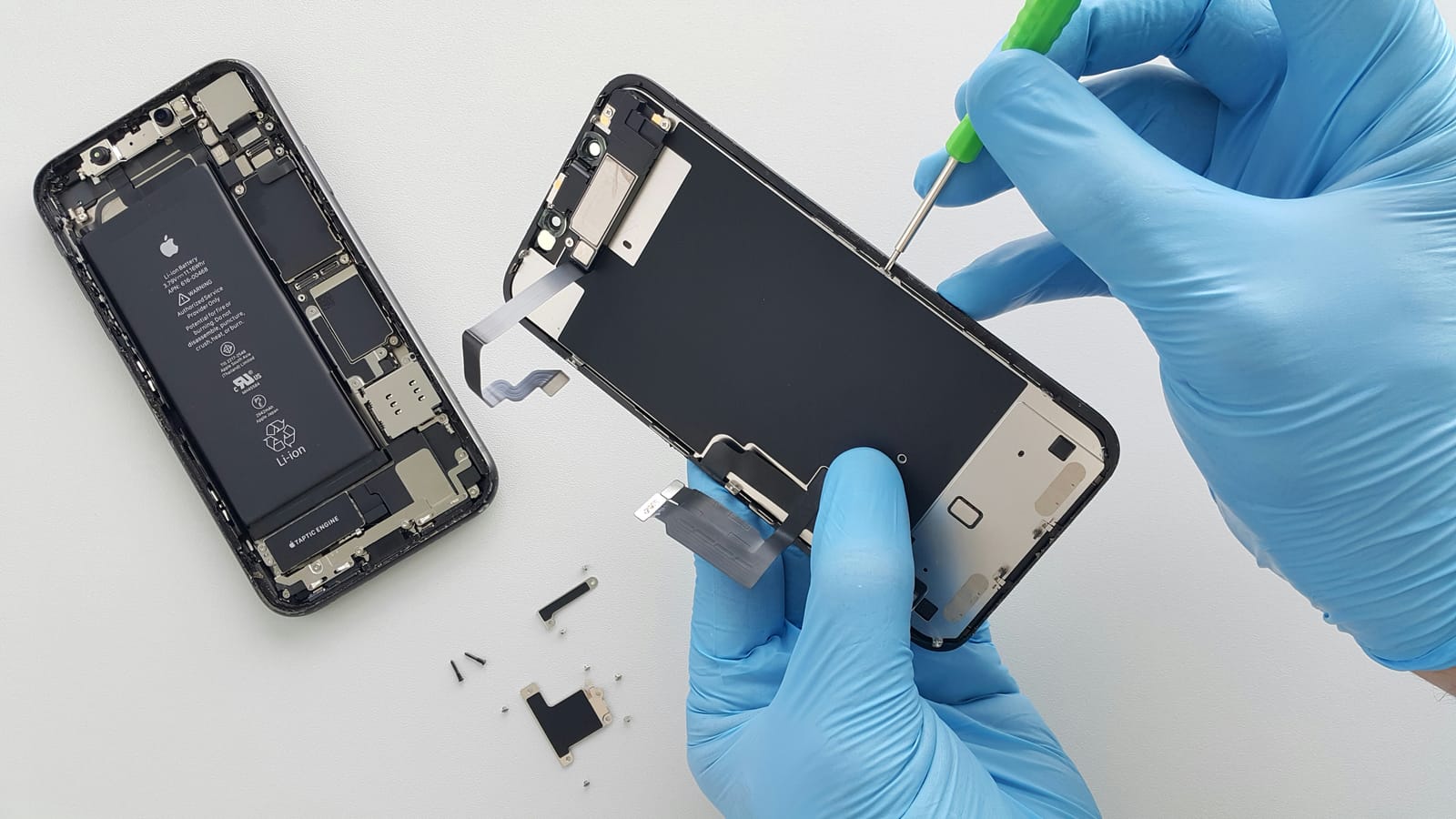 A gloved technician carefully opening an iPhone to replace the screen